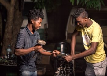 African mechanics repairing an engine with a wrench and hammer