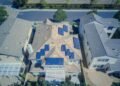 Aerial view of a house with solar panels on its gray and brown roof