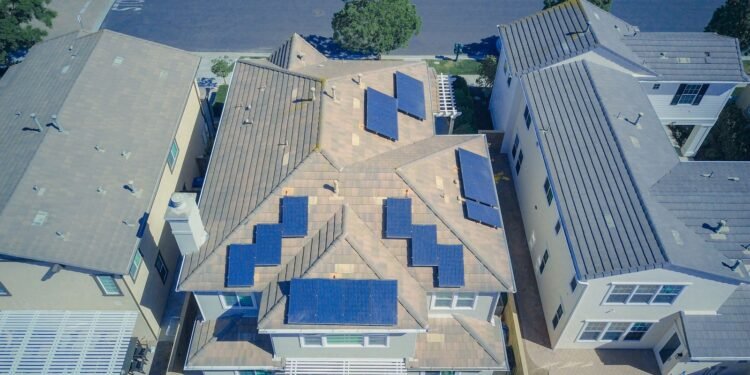 Aerial view of a house with solar panels on its gray and brown roof