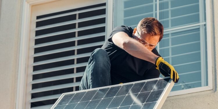 Man working on a house roof while installing a solar panel