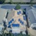 Aerial view of suburban homes with solar panels on their roofs in a sunny neighborhood