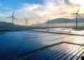 Solar panels and wind turbines silhouetted against the sky at sunset