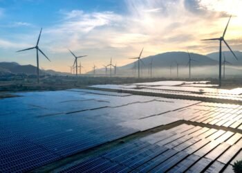 Solar panels and wind turbines silhouetted against the sky at sunset