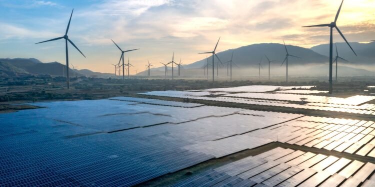 Solar panels and wind turbines silhouetted against the sky at sunset