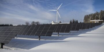 Solar panels standing in a snowy field in winter under a clear sky
