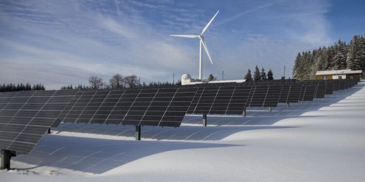 Solar panels standing in a snowy field in winter under a clear sky