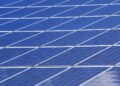 Blue solar panels set up outdoors under a bright, clear sky