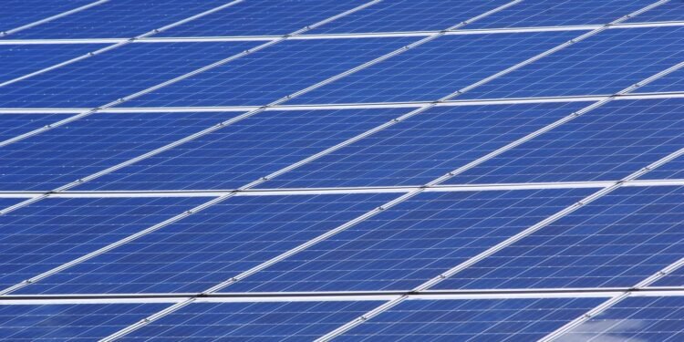 Blue solar panels set up outdoors under a bright, clear sky