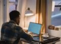 Focused Black man using a laptop at home in the evening