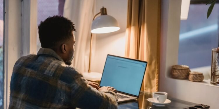 Focused Black man using a laptop at home in the evening