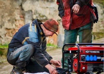 Two technicians working on a red portable power generator outdoors during maintenance