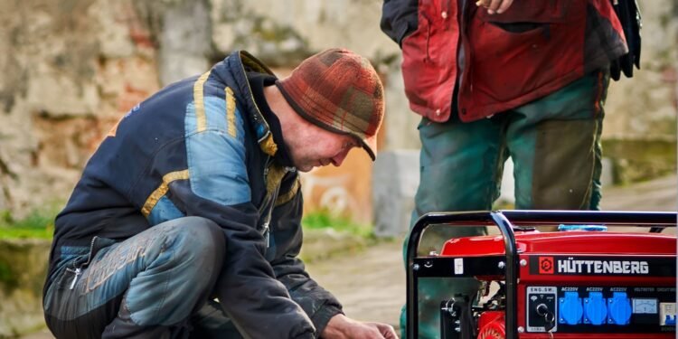 Two technicians working on a red portable power generator outdoors during maintenance