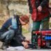Two technicians working on a red portable power generator outdoors during maintenance