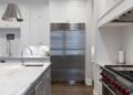 Stainless steel refrigerator standing beside white cabinets in a kitchen