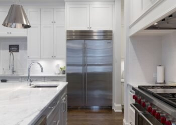 Stainless steel refrigerator standing beside white cabinets in a kitchen
