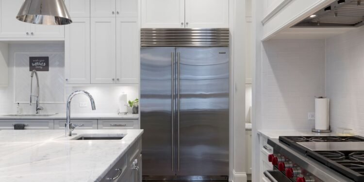 Stainless steel refrigerator standing beside white cabinets in a kitchen