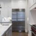 Stainless steel refrigerator standing beside white cabinets in a kitchen