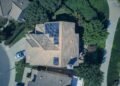 Aerial view of a house roof covered with rows of solar panels