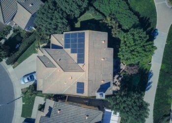Aerial view of a house roof covered with rows of solar panels