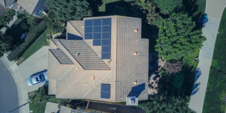 Aerial view of a house roof covered with rows of solar panels