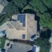 Aerial view of a house roof covered with rows of solar panels
