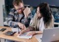 Couple at home reviewing paper bills together with a calculator