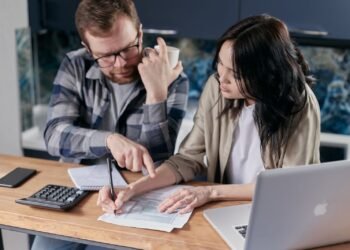 Couple at home reviewing paper bills together with a calculator