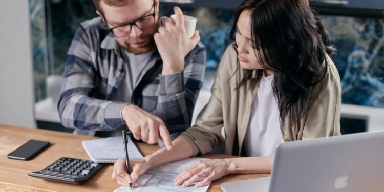 Couple at home reviewing paper bills together with a calculator
