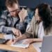 Couple at home reviewing paper bills together with a calculator