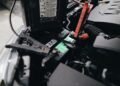 Car battery mounted beside an engine under an open hood