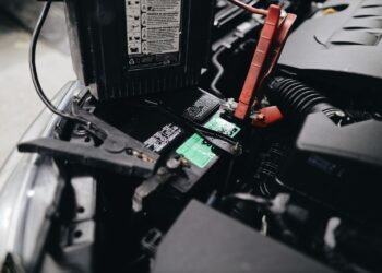 Car battery mounted beside an engine under an open hood