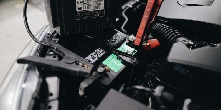 Car battery mounted beside an engine under an open hood