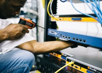 Close-up of a Black technician's hands working carefully with electronic hardware and tools