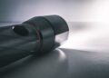 Black handheld flashlight switched on, shining a bright beam of white light