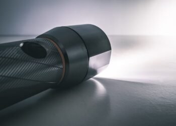 Black handheld flashlight switched on, shining a bright beam of white light