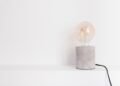 Single light bulb lying on a plain white surface, photographed close up