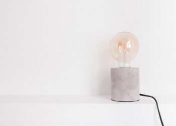Single light bulb lying on a plain white surface, photographed close up