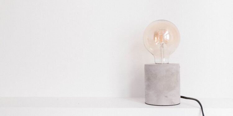Single light bulb lying on a plain white surface, photographed close up