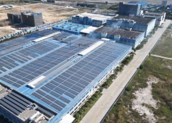 Aerial view of rows of solar panels covering the roof of a large industrial building
