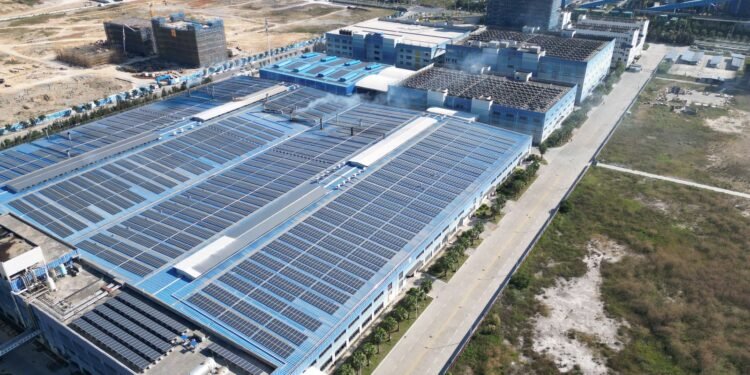 Aerial view of rows of solar panels covering the roof of a large industrial building