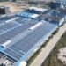Aerial view of rows of solar panels covering the roof of a large industrial building