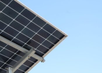 Rear view of a solar panel installation against a clear blue sky