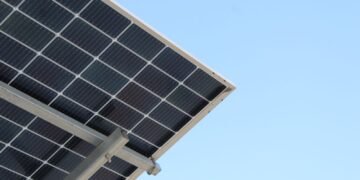 Rear view of a solar panel installation against a clear blue sky