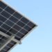 Rear view of a solar panel installation against a clear blue sky
