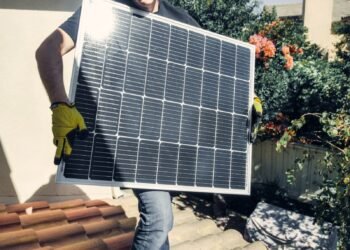 Installer mounting solar panels on the sunny roof of a home