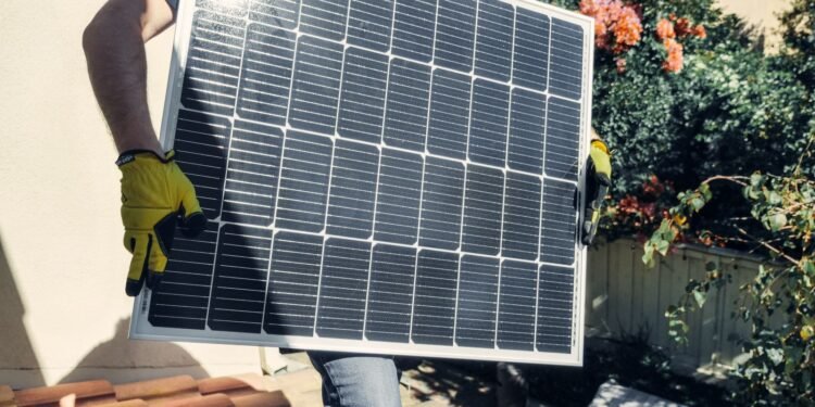 Installer mounting solar panels on the sunny roof of a home