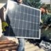 Installer mounting solar panels on the sunny roof of a home
