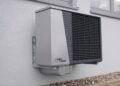 Outdoor air conditioner unit mounted on an exterior building wall in sunlight