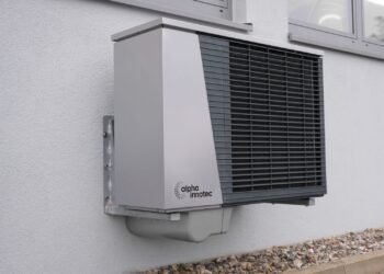 Outdoor air conditioner unit mounted on an exterior building wall in sunlight