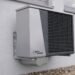 Outdoor air conditioner unit mounted on an exterior building wall in sunlight